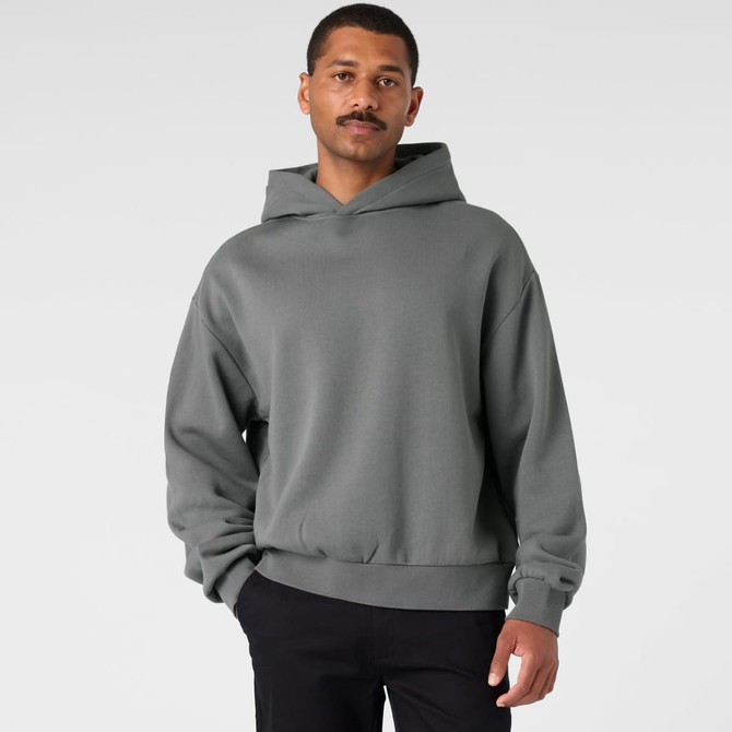 A grey hoodie with a relaxed fit and a hood, featuring long sleeves. The model is standing with a neutral background.