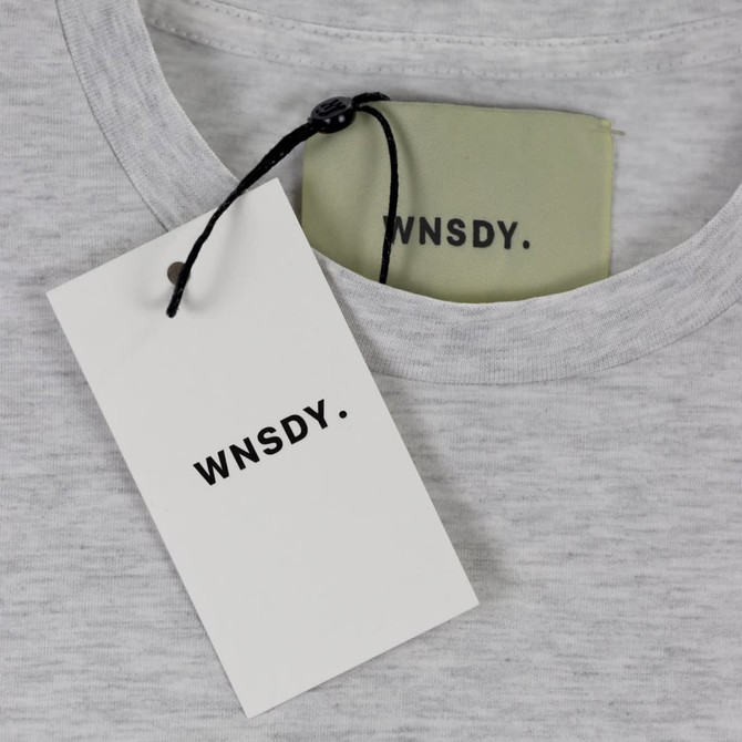 A grey essential tee with a tag and label featuring a logo.