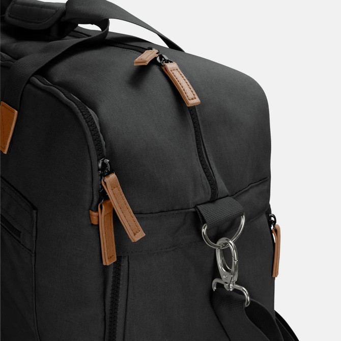 A black duffle bag with tan leather accents and dual zipper pulls, featuring a metal clip and multiple pockets.
