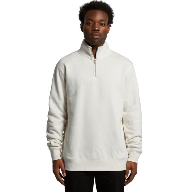 A man wearing a cream-coloured half zip crew jumper. The garment features a stand-up collar and has a logo.