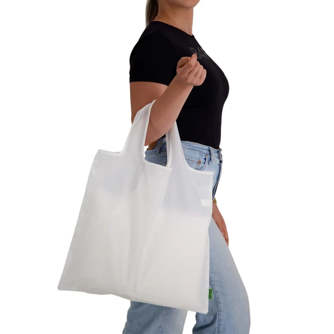 A white reusable grocery bag, held by a person, featuring handles and a simple design with a logo.