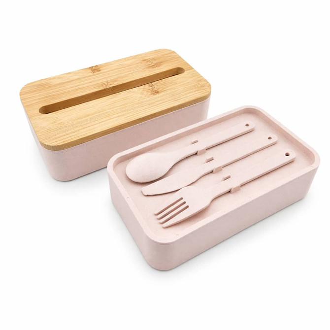 A pink lunch box with a bamboo lid includes a compartment for utensils: a spoon, fork, and knife.