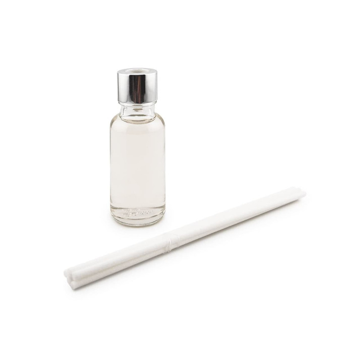 A clear glass bottle with a silver cap and a white reed stick beside it.
