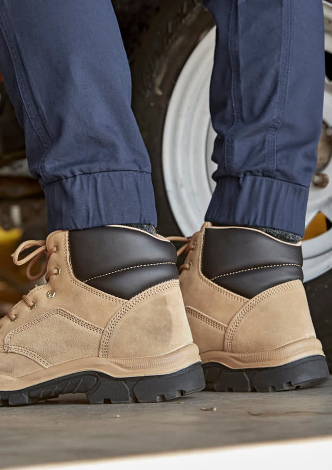 A pair of cuffed navy work pants worn with tan and black boots, set against a vehicle backdrop.