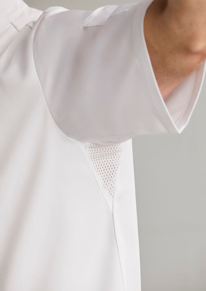 A white short sleeve chef jacket featuring mesh underarm panels and a logo.