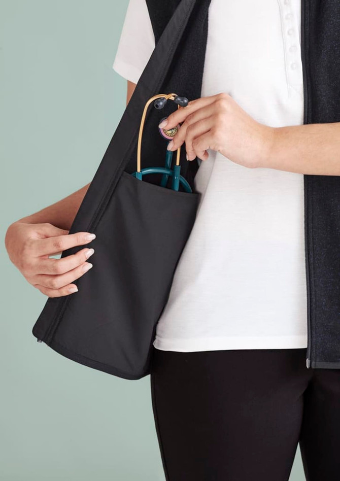A person holds a black vest with a side pocket, featuring blue sunglasses. The vest has a zip front and a sleek design.