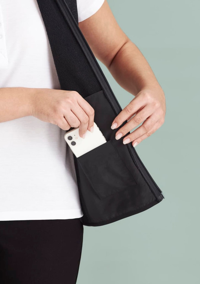 A black women's zip front vest with a hand inserting a phone into a side pocket. The fabric appears smooth and stretchy.