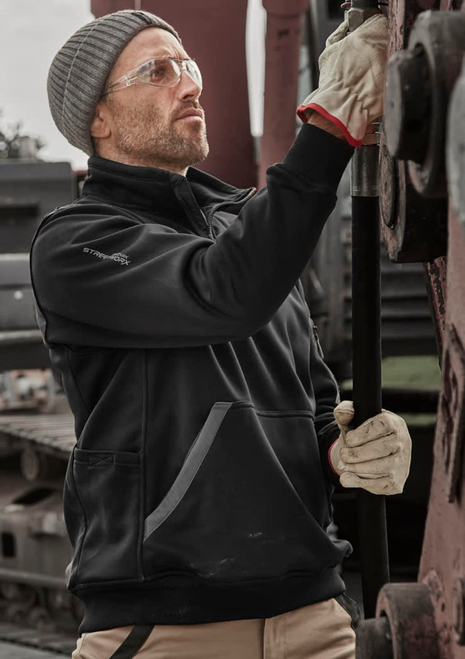 A black water-resistant 1/4 zip pullover worn by a person with safety glasses and gloves, working with machinery.