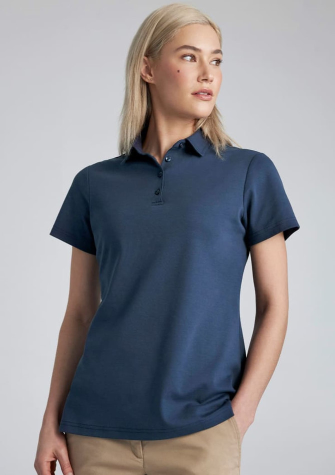 A woman models a navy blue short sleeve polo shirt with a collar and a logo on the chest.