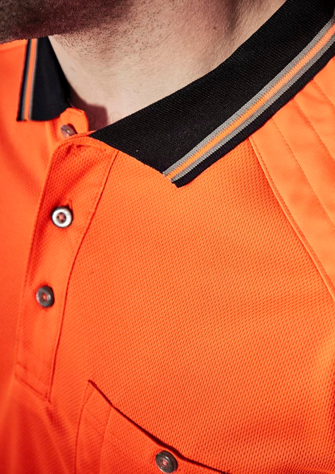 A close-up of an orange short sleeve polo shirt with a black collar and a logo. Features a pocket and buttons.