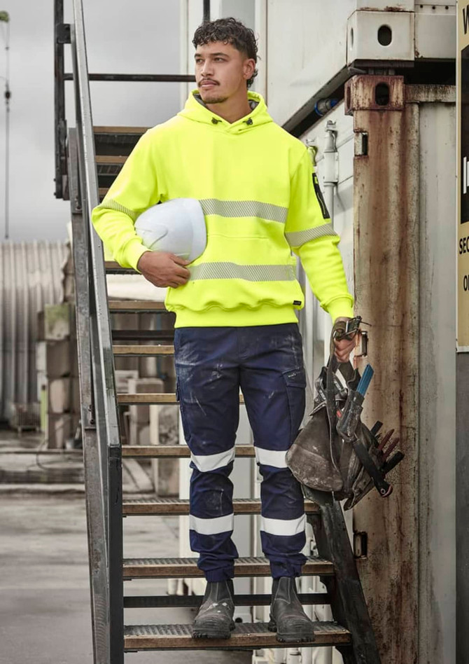 A bright yellow water-resistant hoodie with segmented reflective tape, worn with navy work pants and safety gear.