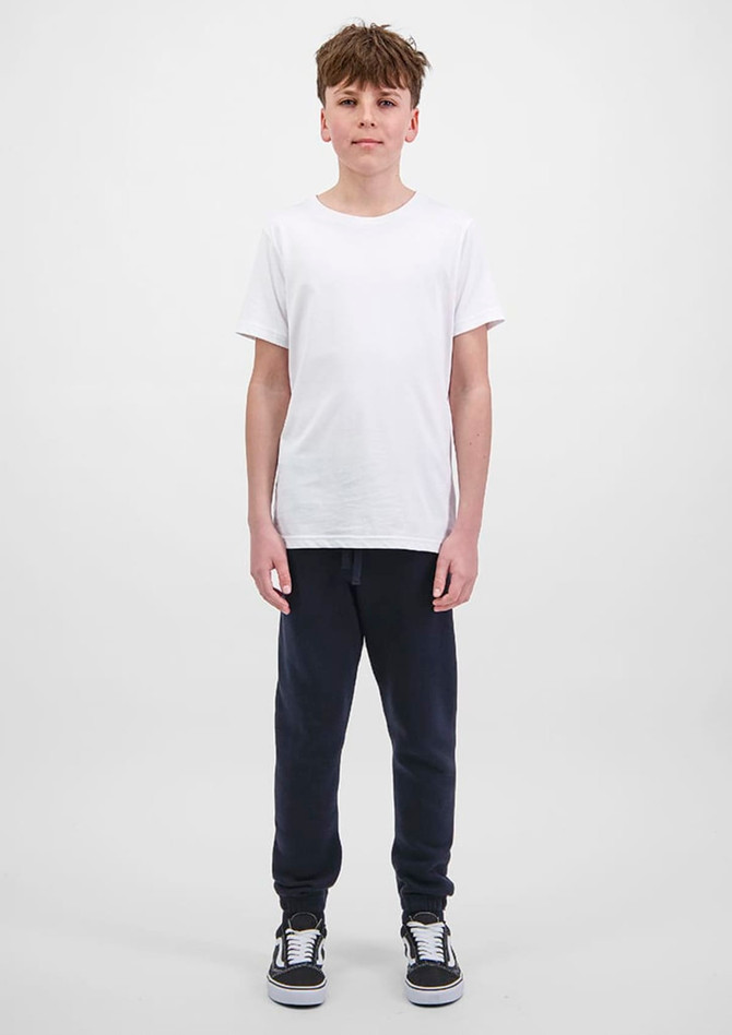 A young person is wearing navy track pants and a plain white t-shirt, standing against a light background.