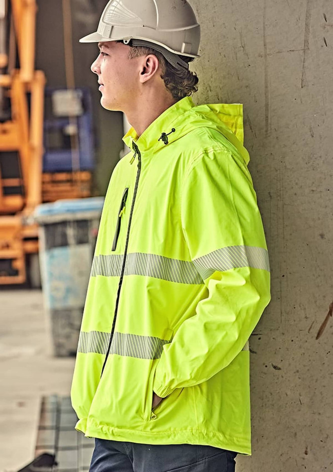 A bright yellow packable rain jacket with reflective stripes, worn by a person standing against a wall.