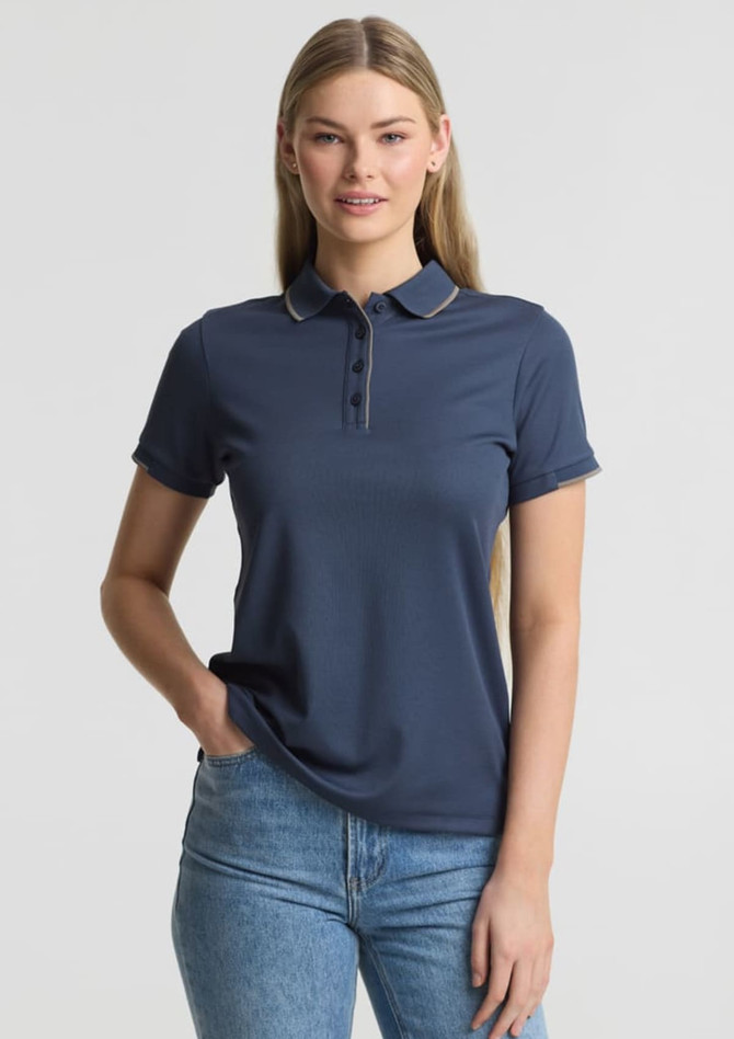 A women's short sleeve polo shirt in navy blue with a collar and a logo. The model is wearing it with jeans.