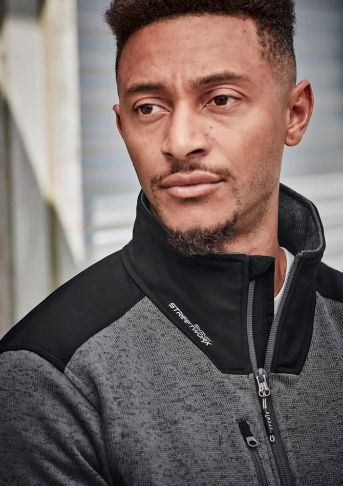 A man wearing a grey and black unisex ½ zip pullover with a reinforced knit design, featuring a logo.