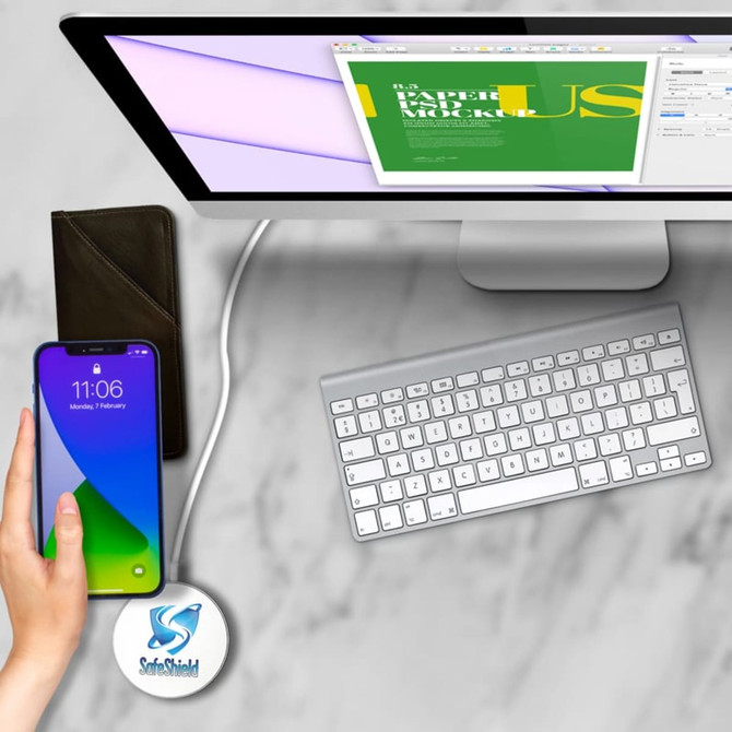 A green and black Tauris 15W magnetic wireless charger is positioned near a smartphone and a keyboard on a desk.