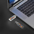A clear Elroy Flash Drive with colourful design plugged into a silver laptop on a black surface.