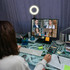 A workspace with a person in front of a computer displaying a video call, featuring a ring light and various office supplies.