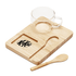 A clear glass cup sits on a bamboo tray with a wooden spoon, featuring a logo on the tray.