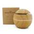 A wooden-patterned diffuser with a round design and a lid, next to a simple, branded box.