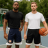 Two men wearing basketball shorts; one in navy with a logo and the other in black, both paired with sporty tops.
