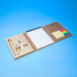 An A5 notepad in a tan folder with a ruler, pen, sticky notes, and multicoloured tabs. It features a logo.