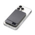 A grey magnetic wireless power bank sits on a smartphone, featuring a sleek design and a logo.