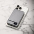 A grey magnetic wireless power bank rests on a smartphone, displaying a sleek and modern design against a marble background.