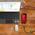 A fast charge and data sync LED cable connects a smartphone to a laptop, with earphones and a mouse nearby.