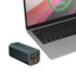 A green power bank with digital display sits next to a laptop, featuring USB ports for charging.
