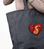 A large black tote bag featuring a heart design, with an embroidered graphic in red and gold tones.
