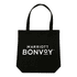 A black tote bag with handles, featuring a logo on the front, placed on a wooden table.