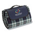 A folded picnic rug in dark blue and green plaid, featuring a handle and a logo.