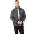A man wearing a grey softshell jacket with a logo, posing in a casual outfit.