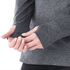 A person wearing a dark grey women's hoodie, featuring thumbholes at the cuffs, showcasing the fabric texture.