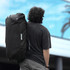A black duffel bag with mid blue accents, featuring a logo, is being carried by a person from behind.