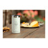 A drink bottle in white with a silver lid, sitting on a wooden table beside snacks and treats.