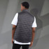 A lightweight, packable insulated puffer vest in black, featuring a logo, with a model wearing a white t-shirt underneath.
