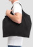 A black nylon tote bag is being carried by a person, featuring a simple design and a logo.