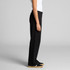 Cuffless black track pants featuring an elastic waistband and a fitted silhouette. Includes a logo on the garment.