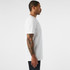 A white t-shirt displayed on a male model, showcasing a side view and a simple design with a logo.