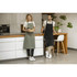 A green apron and a black apron worn by two people in a modern kitchen setting, featuring a logo on the aprons.