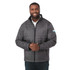 A man wearing a grey puffer jacket with a zip front and a logo on the sleeve.
