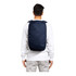 A person wearing a navy blue backpack, featuring padded shoulder straps and a simple design. The backpack has a logo.
