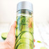 A drink bottle with a silver lid, featuring clear body filled with water, cucumber slices, and mint leaves.