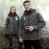 A pair of models wearing grey insulated softshell jackets, with hoods, in a misty outdoor setting.