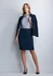 A woman in a navy 3/4 sleeve shirt and matching skirt stands confidently, wearing a blazer and high heels.
