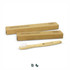 A bamboo toothbrush with a wooden handle and white bristles, accompanied by two brown cardboard boxes.