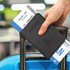 A black passport wallet holding travel documents, resting on the handle of a suitcase. It features a logo.