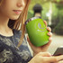 A drink bottle in vibrant green with a metal rim, held by a person while using a smartphone. Features branding.